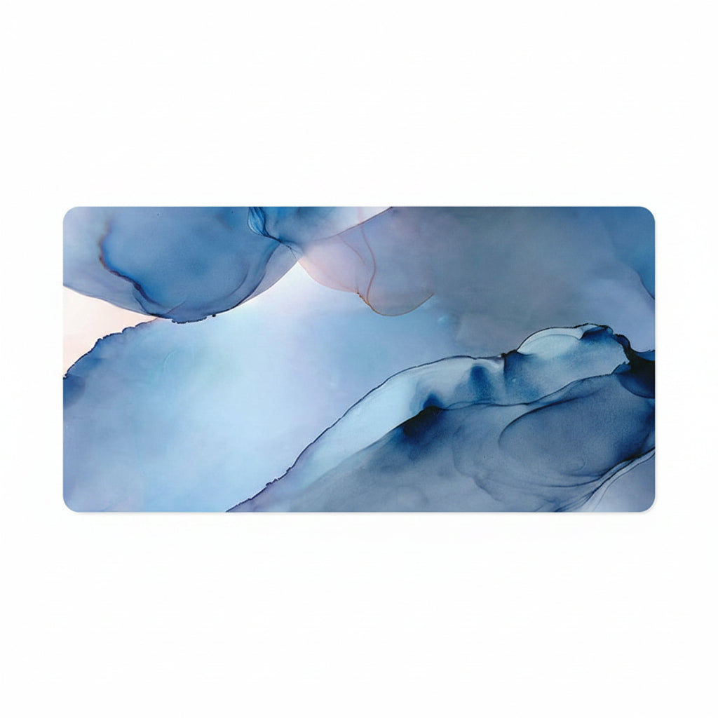 A rectangular desk mat with rounded corners featuring an abstract ink-blot style design in shades of blue, navy, and white, shown on a solid white background.