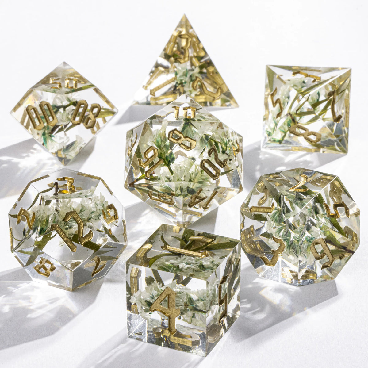 Set of clear polyhedral dice with gold numbers on a white background