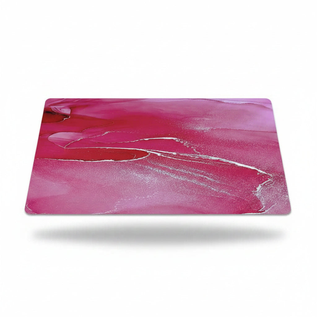 A rectangular desk mat with rounded corners featuring a vibrant magenta pink and red fluid acrylic pour design with white swirls, shown floating on a white background with a soft drop shadow.