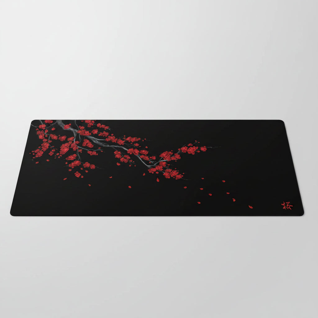 Black desk mat with red cherry blossom design on a dark background