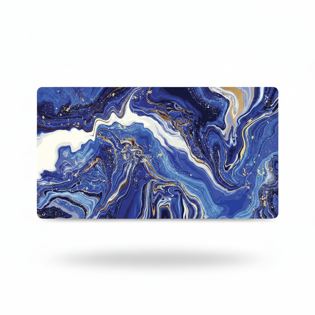 A rectangular desk mat featuring an abstract marbled design in deep blue, white, and gold with small scattered gold speckles, shown on a clean white background with a soft drop shadow.