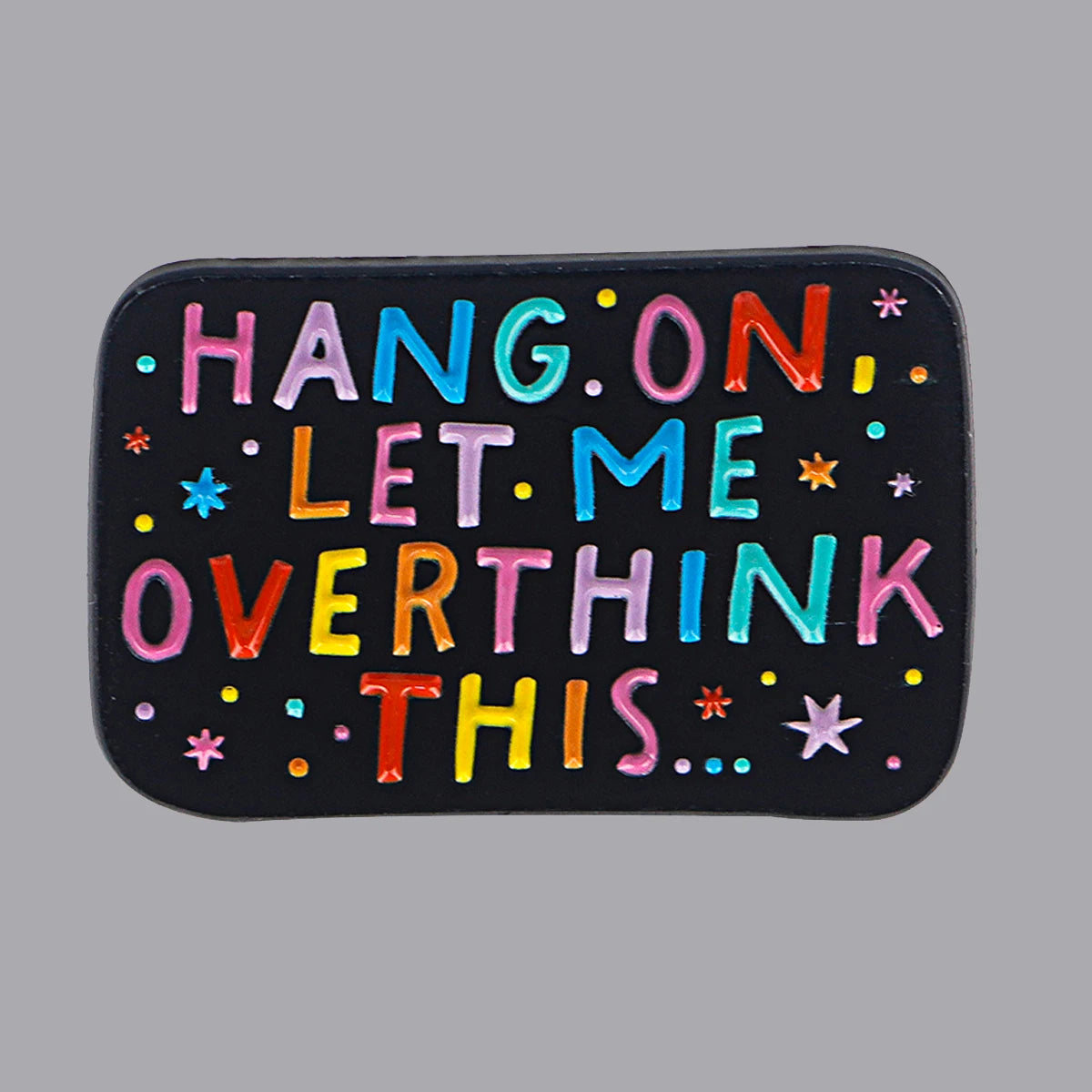 Black rectangular enamel pin with colourful text 'Hang on, let me overthink this…'