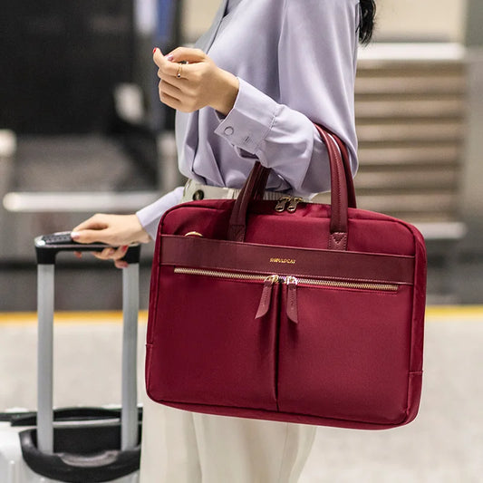 Burgundy laptop shoulder messenger bag carried beside a suitcase